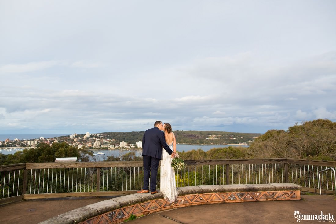 A bride and groom share a kiss at a lookout