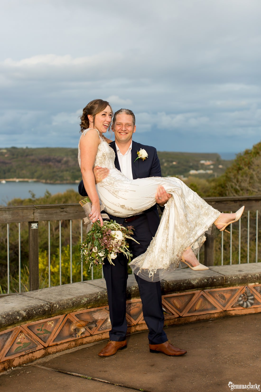 A groom holds up his bride at a lookout