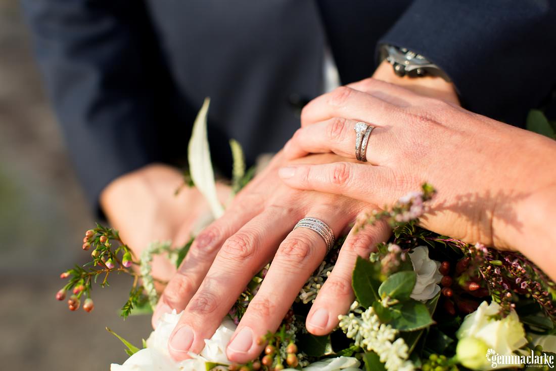 A close up of a bride and groom's hands showing off their rings