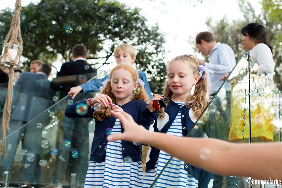 Two young girls in matching outfits blowing bubbles