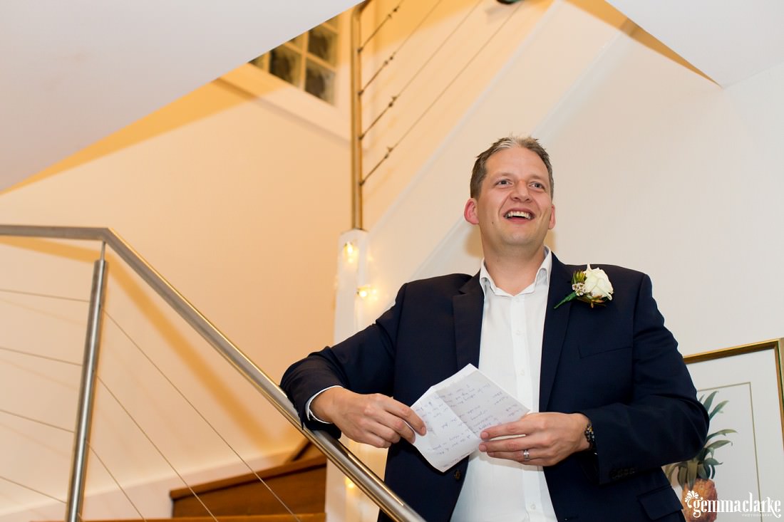 A groom standing on stairs making a speech