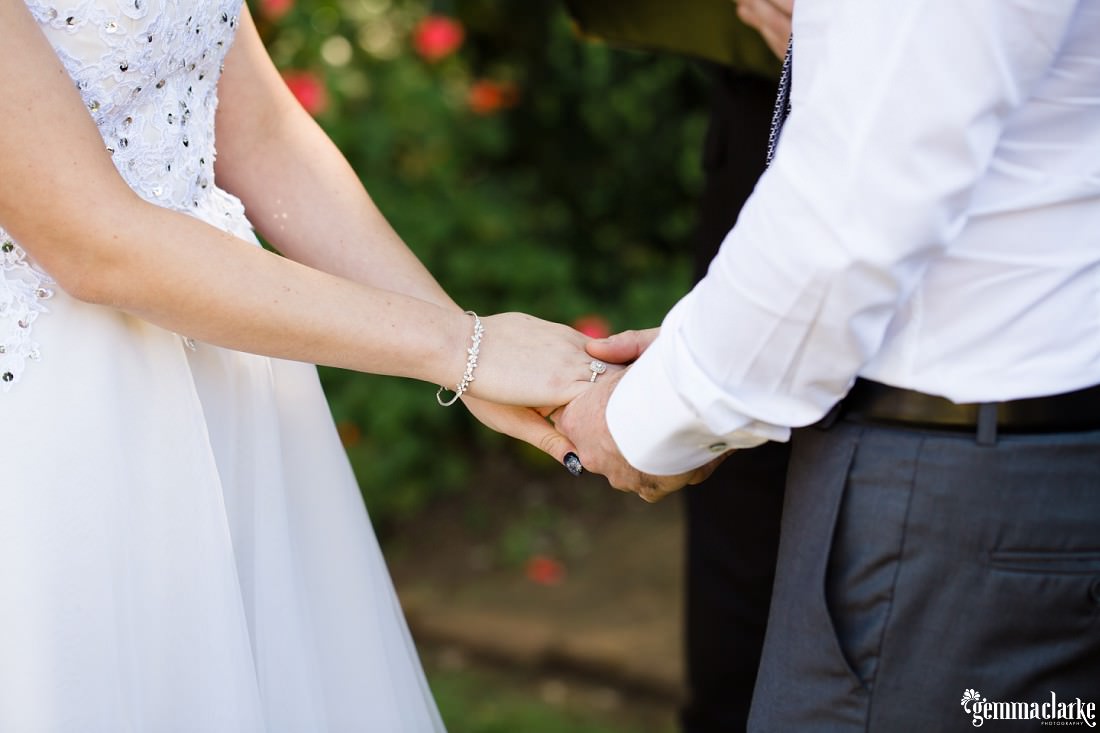 A bride and groom holding hands during their wedding ceremony