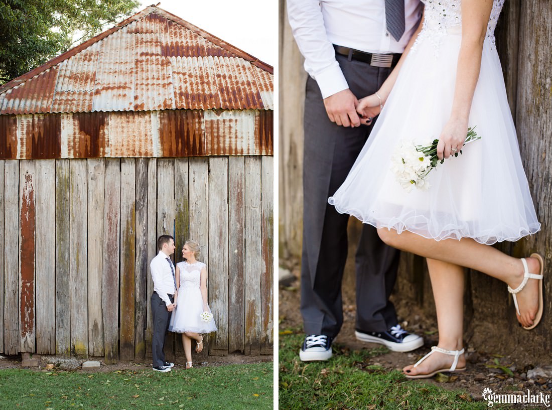 A bride and groom standing together in front of an old wood and corrugated iron structure