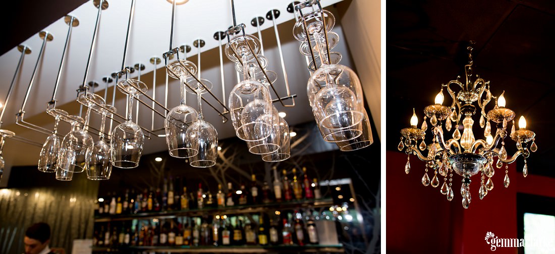 A chandelier, and wine glasses hanging above a bar