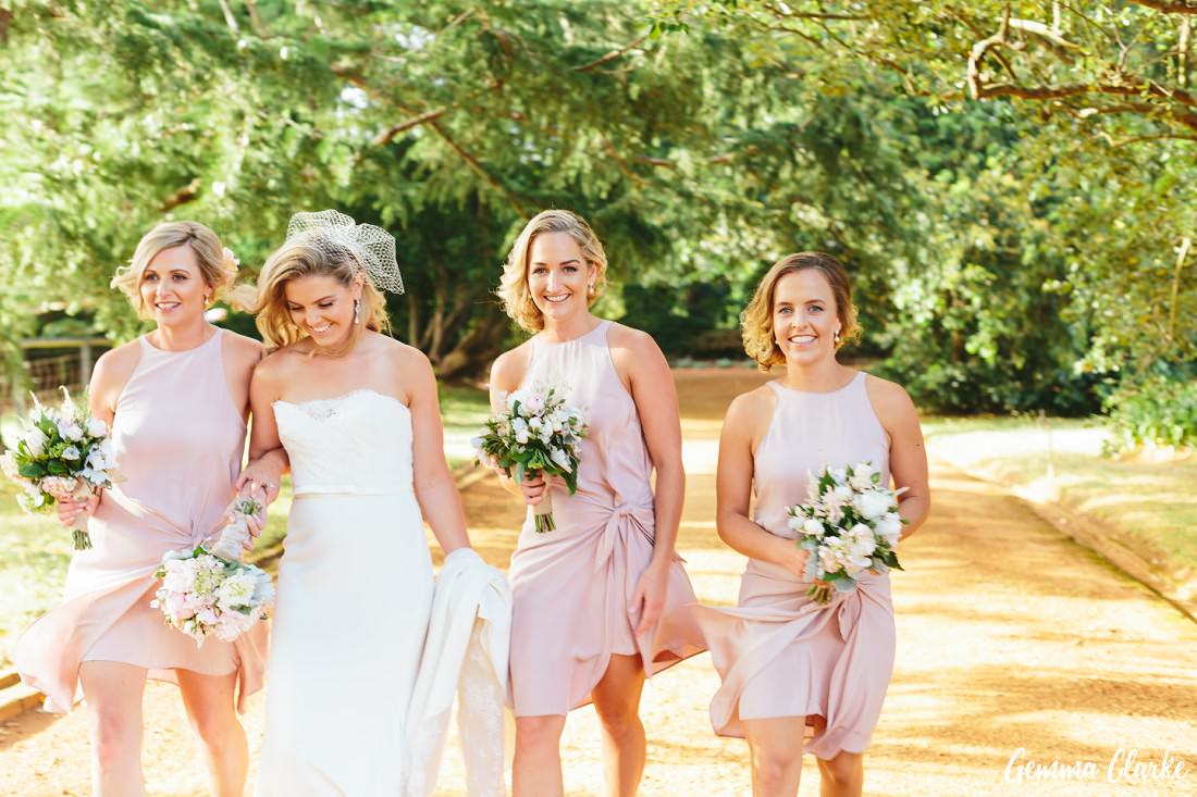 Bride and Bridesmaids looking relaxed as they walk down the orange road at this Bendooley Estate Wedding