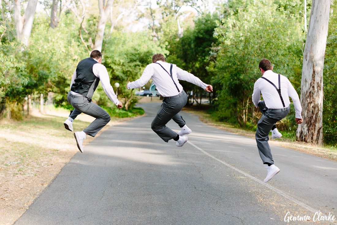 Fun groomsmen jumping and clipping their heels together at the driveway to this Belair Park Wedding