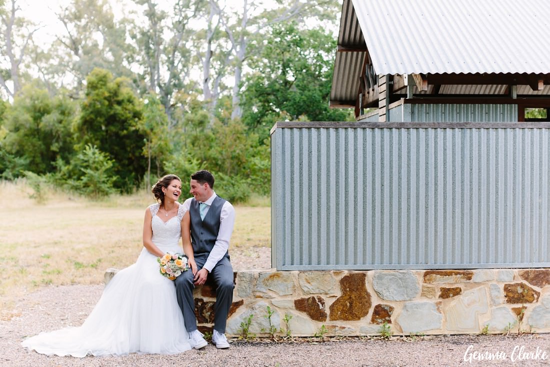 Bride and Groom sitting on a sandstone wall and laughing at this Belair Park Wedding