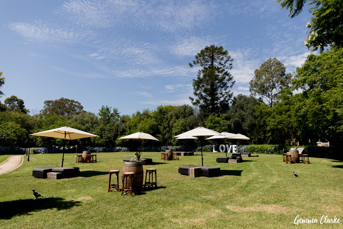 Guest mingling garden set up with bar stools, wine barrells and relaxing seats and umbrellas at this Burnham Grove Estate Wedding