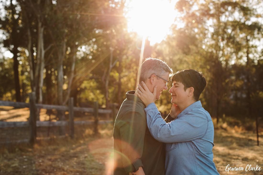 The sun shines on this lovely couple as they embrace with their hands on each other's face at this same sex couple's portraits session