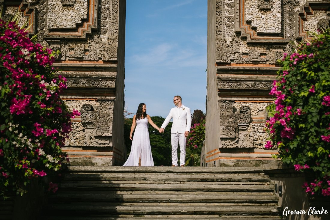 Bride and Groom holding hands at the opening of Hindu temple in Bali at this three minute wedding photo shoot with colourful flowers