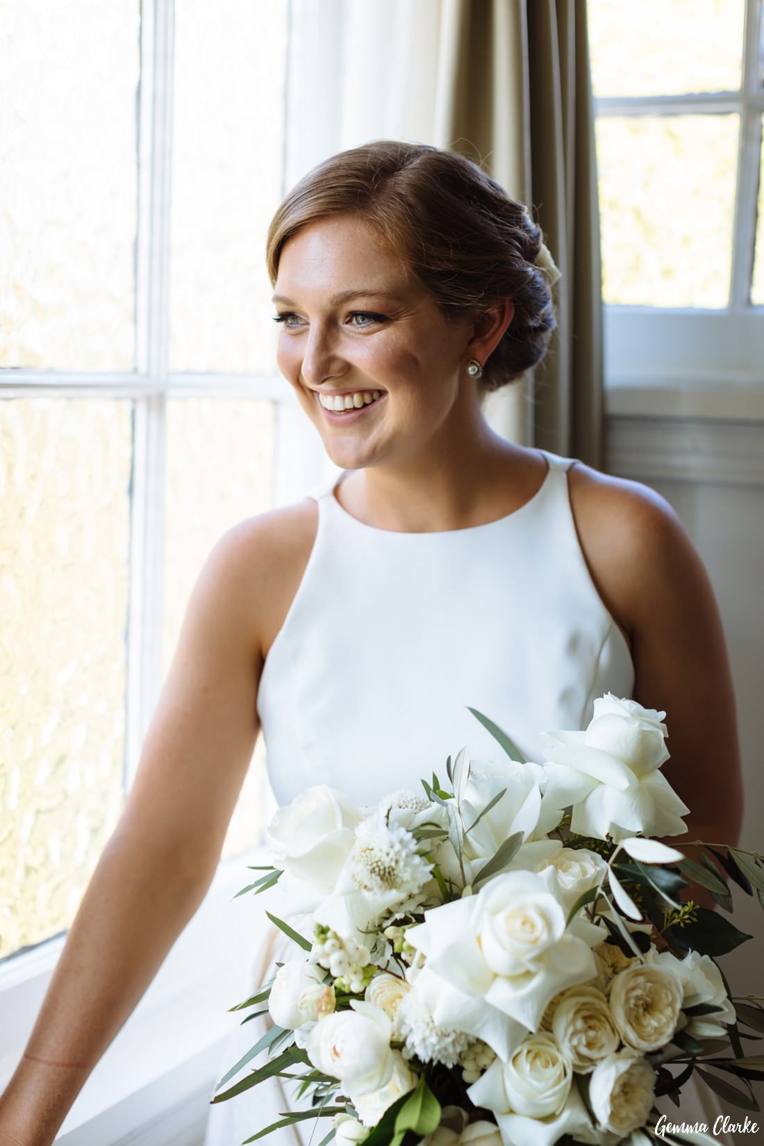 Bride at the window with a big bunch of white flowers at this Peppers Manor House Wedding