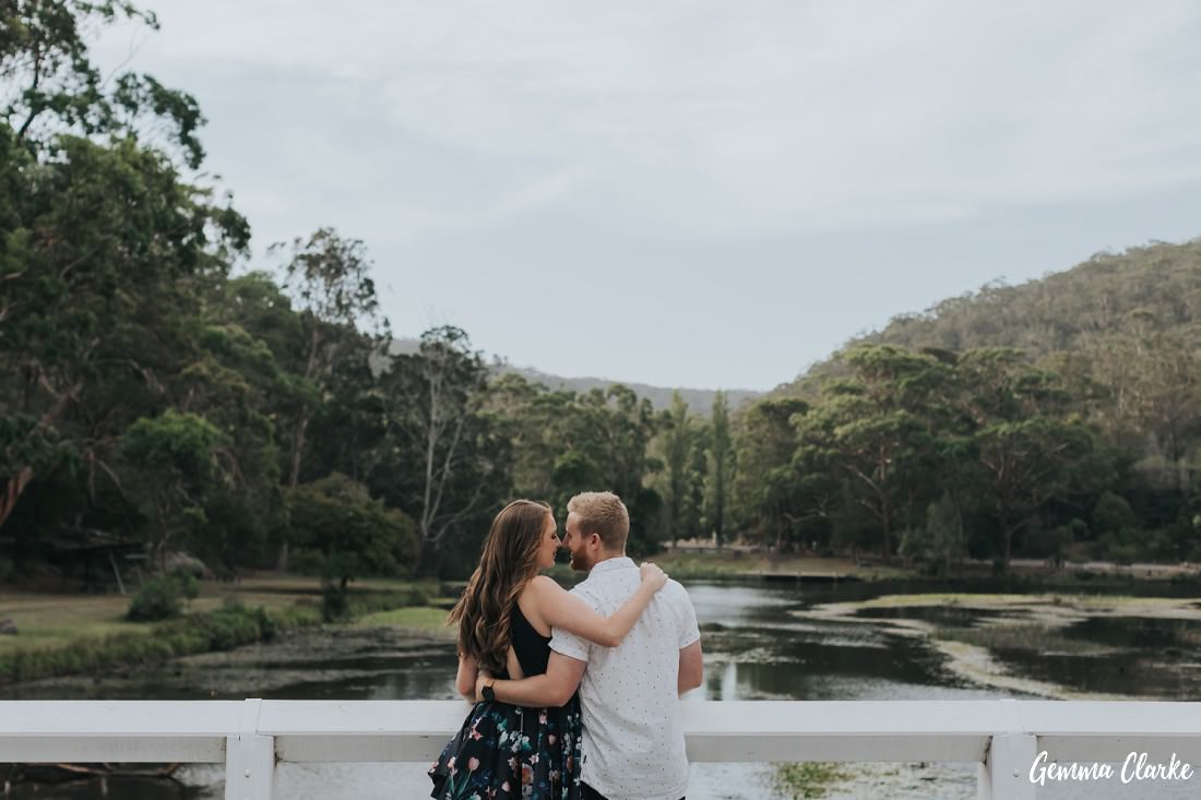 Couple hug on a white bridge overlooking Audley, Sydney Engagement Photos