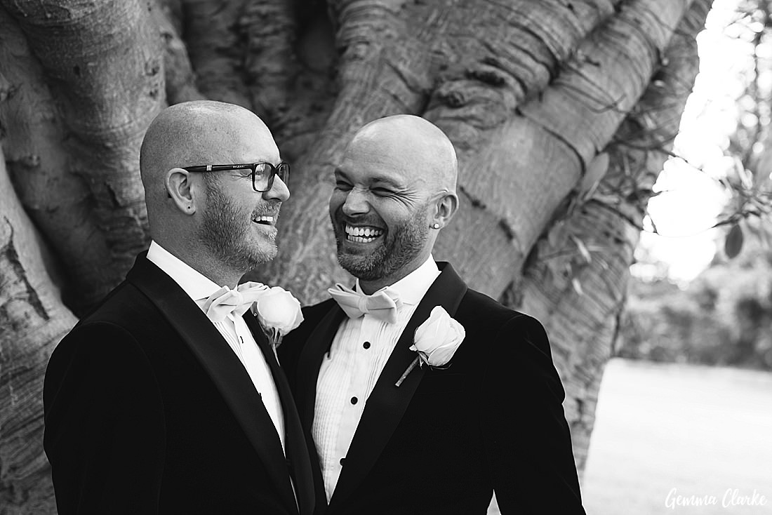 Black and white close up of two grooms enjoying a laugh in the Royal Botanic Gardens at this Sydney Gay Wedding