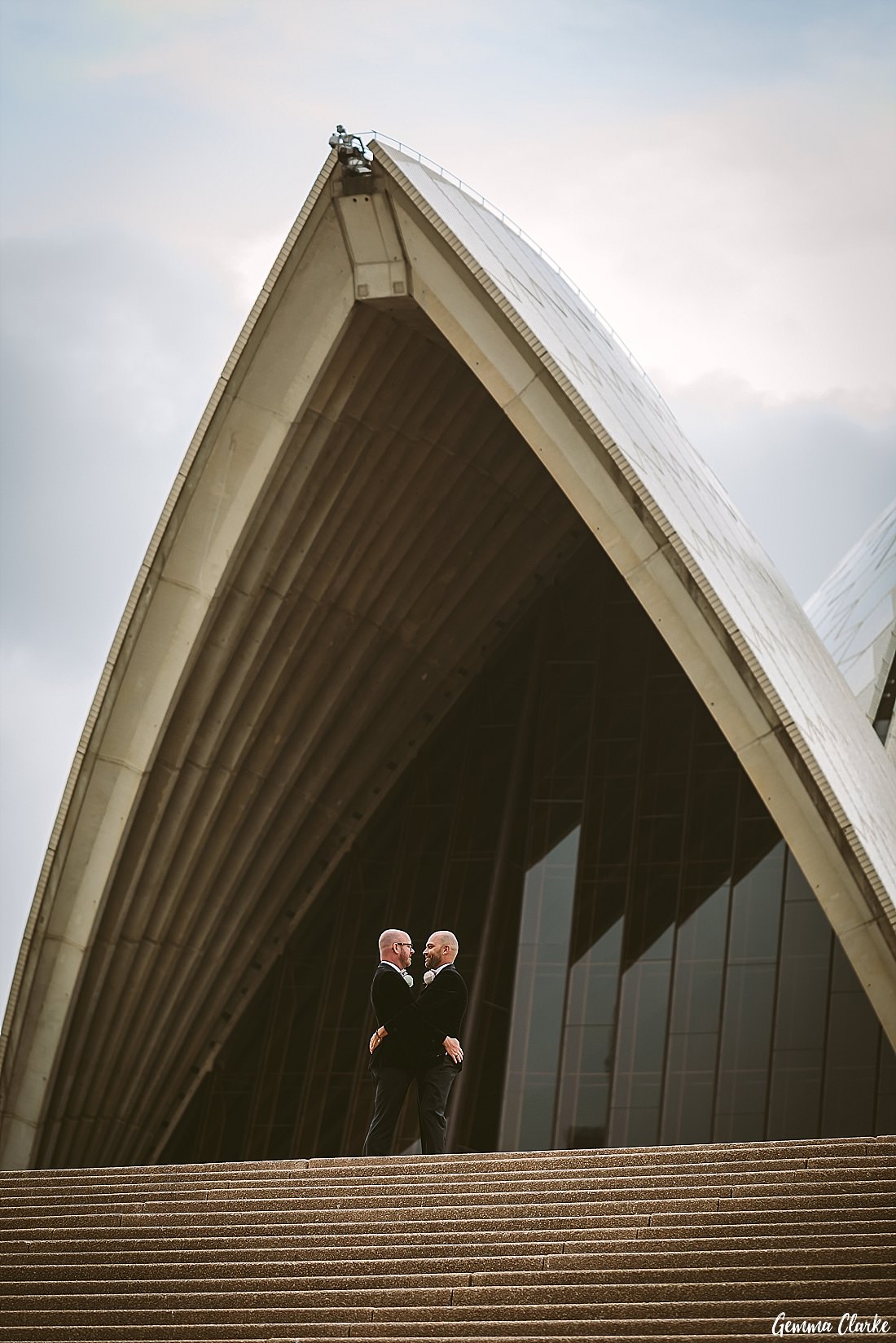 Two grooms cuddling in front of the Sydney Opera House at this Sydney Gay Wedding