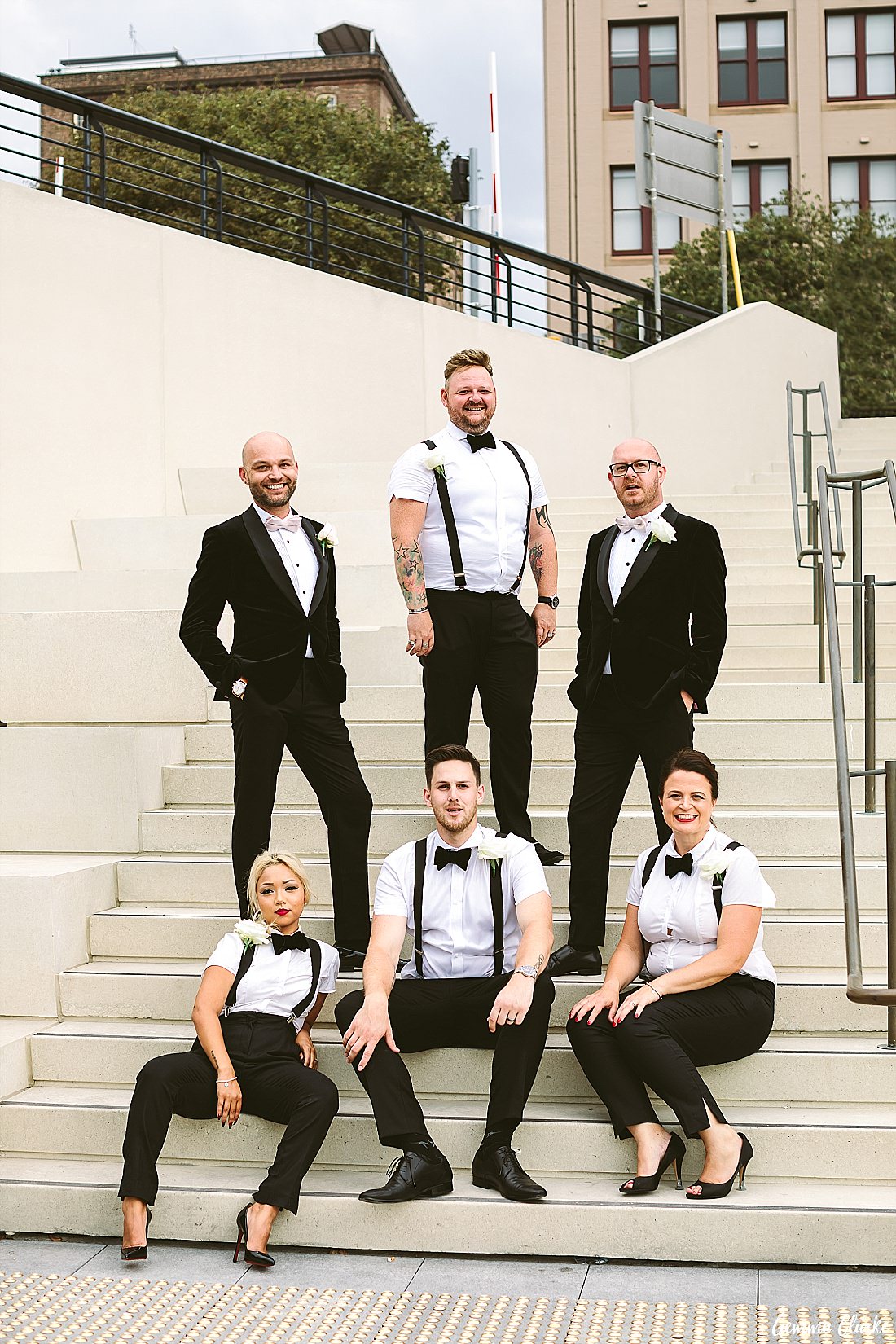 Wedding party wearing short sleeves, bow ties and suspenders while the two grooms rock a velvet jacket tuxedo at this Sydney Gay Wedding
