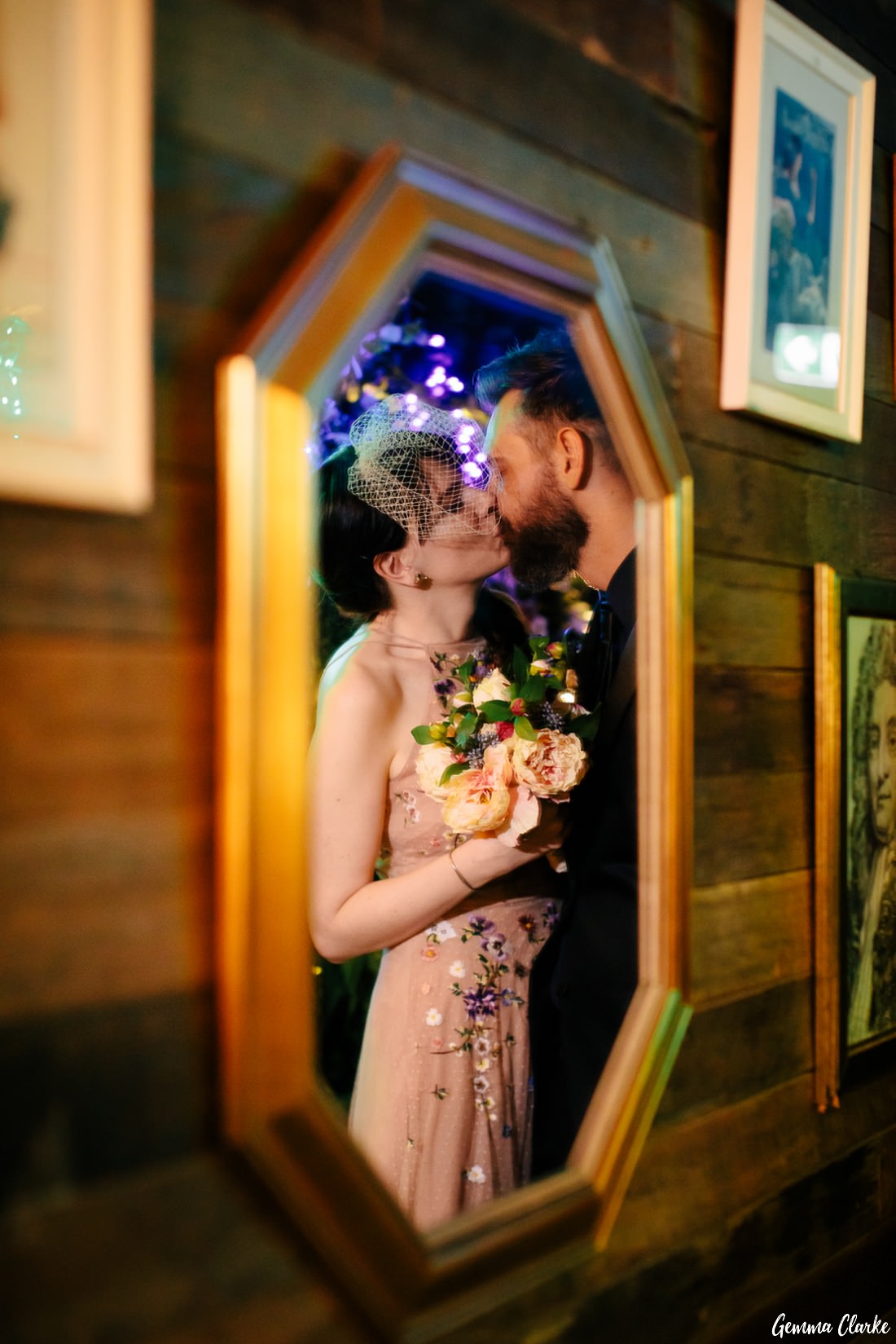 The happy couple kissing and framed with the mirror at this rooftop bar wedding