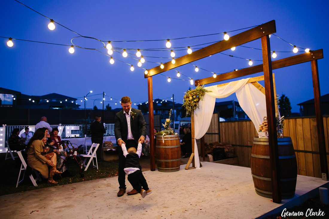 The groom spins his son around as it gets dark at this western sydney backyard wedding