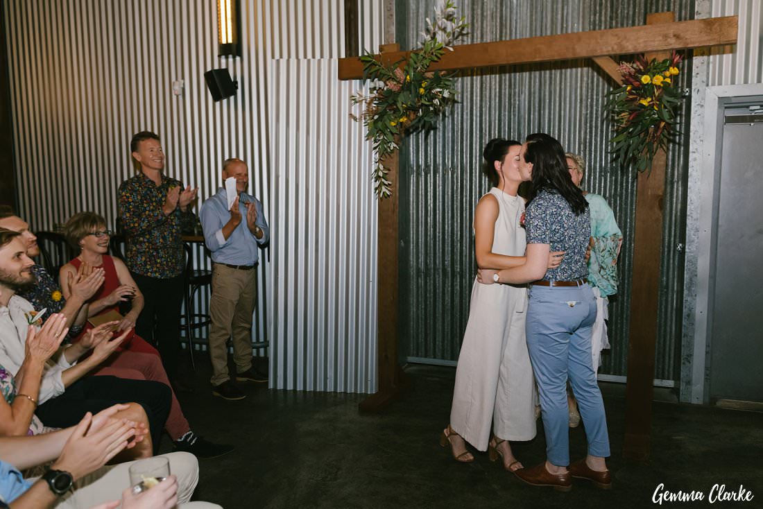 Corrugated iron background for this wedding ceremony as the couple have their first kiss at Archie Rose Distillery 