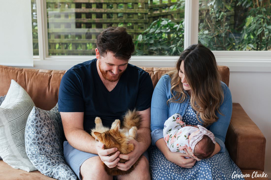 Cradling the baby and the furbaby on the couch - At Home Newborn Photos